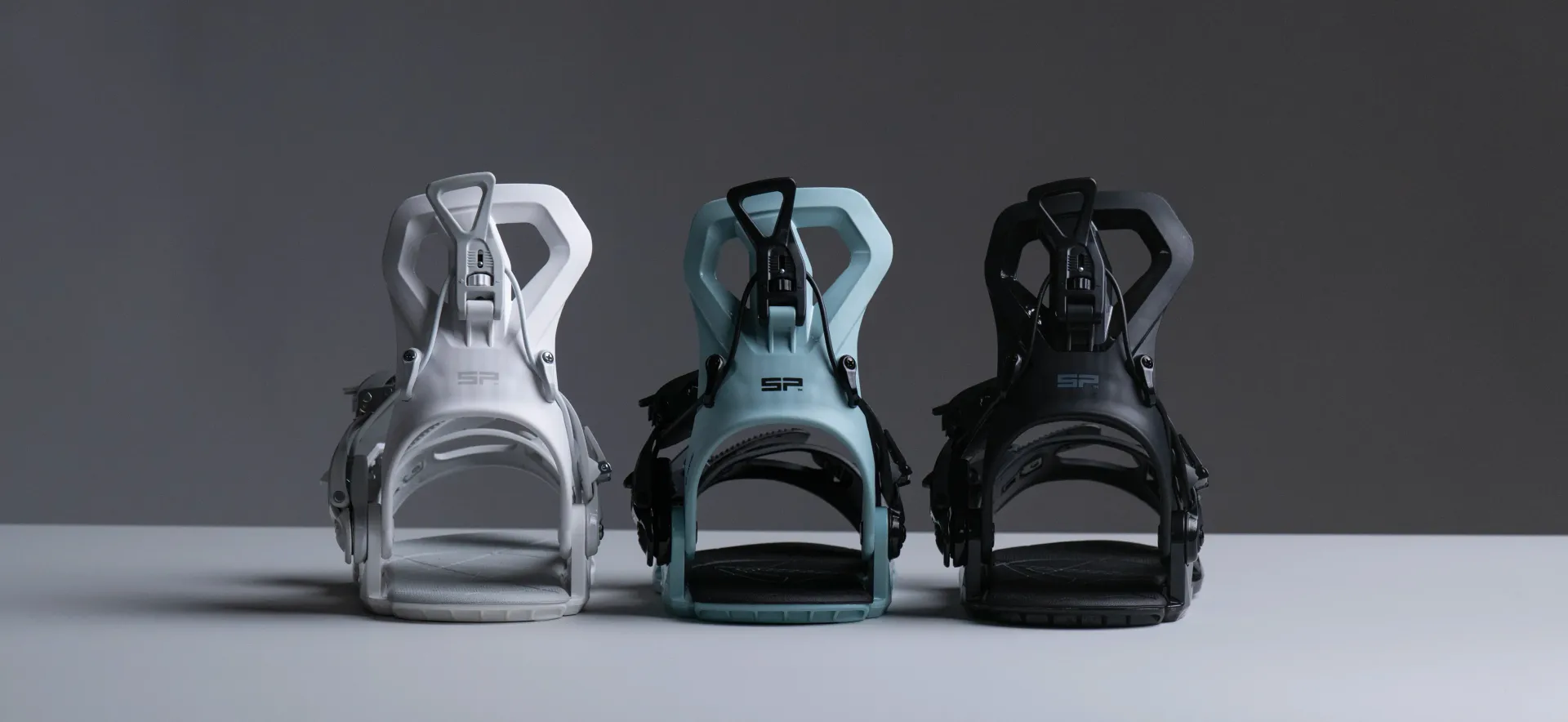 Three SP FASTEC bindings side by side in white, ice blue and black, front view in a studio.